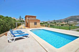 a swimming pool with lounge chairs and a house at Marques - holiday home with private swimming pool in Benitachell in Benitachell