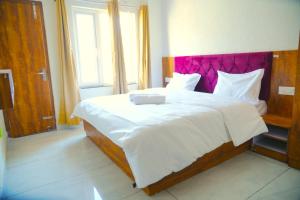a bedroom with a large bed with a purple headboard at Bunk Hostel Tapovan in Rishīkesh