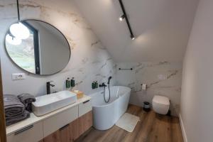 a bathroom with a tub and a sink and a mirror at Sadova Chalet in Sadova +15 photos