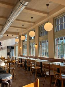 a dining room with tables and chairs and windows at Hotel Bloemendaal by BHC in Bloemendaal