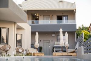 a house with a swimming pool with umbrellas at Theros Suites in Dhiminión