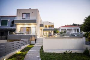a house with a white fence and a pathway at Theros Suites in Dhiminión