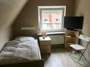 a bedroom with a bed and a tv and a window at Handwerkerunterkunft in Elmshorn