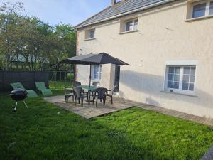 a patio with a table and chairs and an umbrella at Nid de Coucou in Cernoy-en-Berry