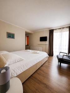 a bedroom with a large white bed and a chair at Casa Liniștea Pădurii in Gura Văii