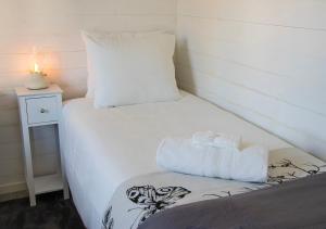 a small bedroom with a white bed and a night stand at Tiny House Near Skokloster Castle in Uppsala