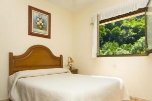 a white bedroom with a bed and a window at La Veiga Apartamentos Turísticos in La Riera