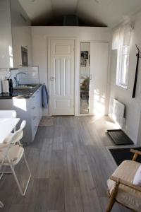 a kitchen with wooden floors and a white door at Tiny House Near Skokloster Castle in Uppsala