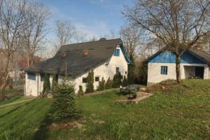 a white house with a black roof on a green field at Casa Plaiul Cailor: Rustic Mountain Hideaway in Proviţa de Sus