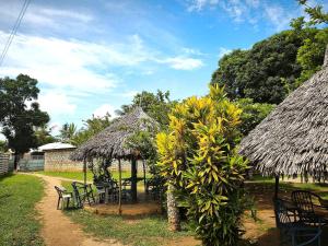 a garden with a table and chairs and a thatch hut at HOTSPOT inn - Malindi in Malindi