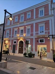 a pink building with people walking in front of it at Antica Dimora Petito Luxury Suites in Matera