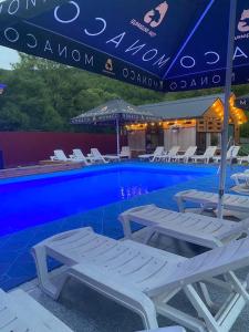 a pool with white lounge chairs and an umbrella at Vivat in Solochyn