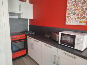 a kitchen with a microwave and a red wall at Ferienwohnung Friederike Luise in Bad Freienwalde
