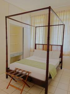 a bedroom with a four poster bed and a chair at Bungles Ungalow in Castries
