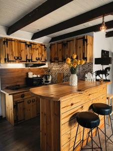 a kitchen with wooden cabinets and a counter with stools at Domki Na Ranczo in Gniezno