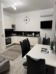 a kitchen with a white table and black chairs at ILK Residence in Balatonalmádi