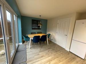a dining room with a table and blue chairs at 3 Beds with off-street parking for 2 cars, fast Wifi, sleeps 6 in Ashby de la Zouch
