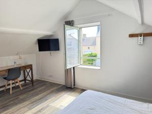 a bedroom with a bed and a desk and a window at Logis Hôtel La Demeure du Perron in Quettehou +193 photos