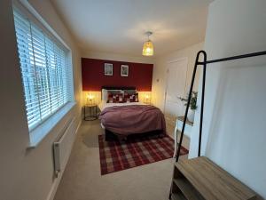 a bedroom with a bed with red walls and a window at 3 Beds with off-street parking for 2 cars, fast Wifi, sleeps 6 in Ashby de la Zouch