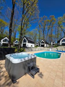 a hot tub on a patio next to a swimming pool at Treehouses in Skorochow