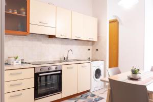 a kitchen with white cabinets and a sink and a dishwasher at Casa Nel Blu in SantʼAlessio Siculo