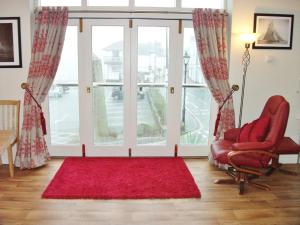 a living room with a red chair and a large window at Watch House in Fowey