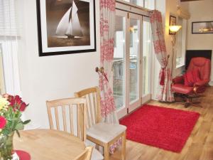 a living room with a table and a red chair at Watch House in Fowey