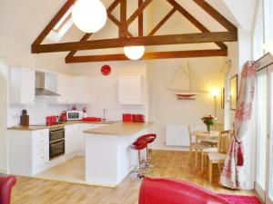 a kitchen with white cabinets and a table with a red chair at Watch House in Fowey