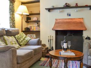 a living room with a couch and a table with wine glasses at Yew Tree Cottage in Arford