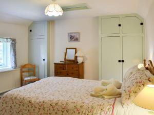 a bedroom with a bed with a dresser and a mirror at Yew Tree Cottage in Arford