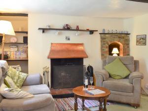a living room with two chairs and a fireplace at Yew Tree Cottage in Arford +8 photos
