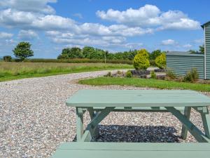 a green picnic table sitting on a gravel road at Beech - Uk47622 in Hunmanby