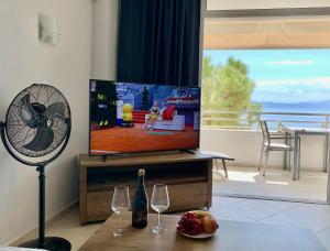 a living room with a flat screen tv and two wine glasses at Sea view studio in Loutraki
