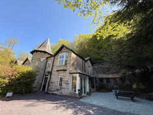 an old stone house with a bench in front of it at 1 Bron Rhedyn Holiday Cottage in Betws-y-coed