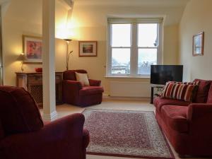 a living room with two red chairs and a television at Causey Pike in Keswick