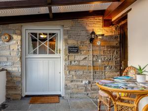 a stone house with a white door and a table at Orchard Cottage - Uk30437 in Kingsbury Episcopi