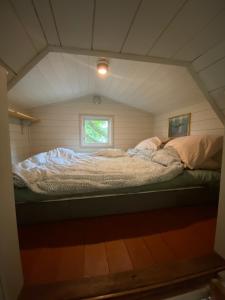 a bed in a small room with a window at Fint Tiny house på Österlen in Sankt Olof