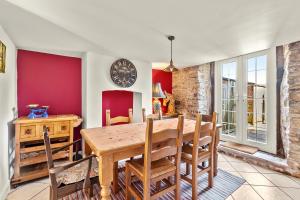 a dining room with a table and a clock on the wall at John Brown Cottage in Skipton