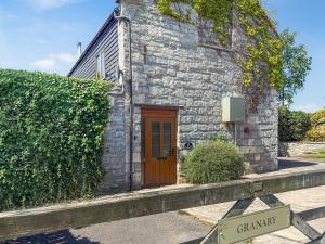 a small stone building with a wooden door and a sign at The Granary - Uk50171 in Mare Green