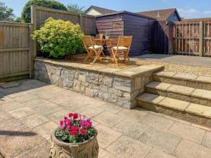 a patio with a table and chairs and flowers at The Swallows - Uk50177 in Mare Green