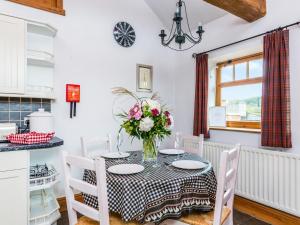 a dining room with a table with a vase of flowers at Anvil Cottage in Louth