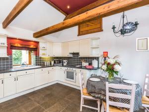 a kitchen with white cabinets and a table with a vase of flowers at Anvil Cottage in Louth