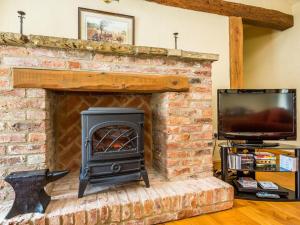 a brick fireplace with a stove and a tv at Anvil Cottage in Louth
