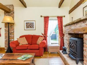 a living room with a red couch and a fireplace at Anvil Cottage in Louth