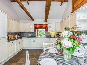a kitchen with a table with a vase of flowers at Anvil Cottage in Louth +7 photos