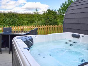 a hot tub in a backyard with a table at Sycamore - Uk47621 in Hunmanby