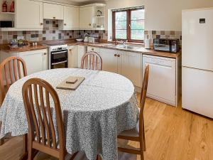 a kitchen with a table and chairs and a white refrigerator at The Wrens - Uk50181 in Mare Green