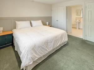 a bedroom with a large white bed and a bathroom at The Wrens - Uk50181 in Mare Green