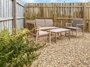 a patio with two chairs and a table and a fence at The Wrens - Uk50181 in Mare Green +3 photos