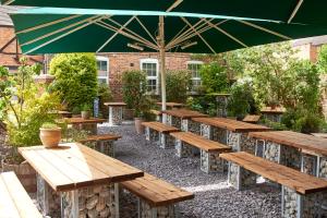 a group of wooden tables and a large umbrella at The Angel Inn Hotel in Pershore